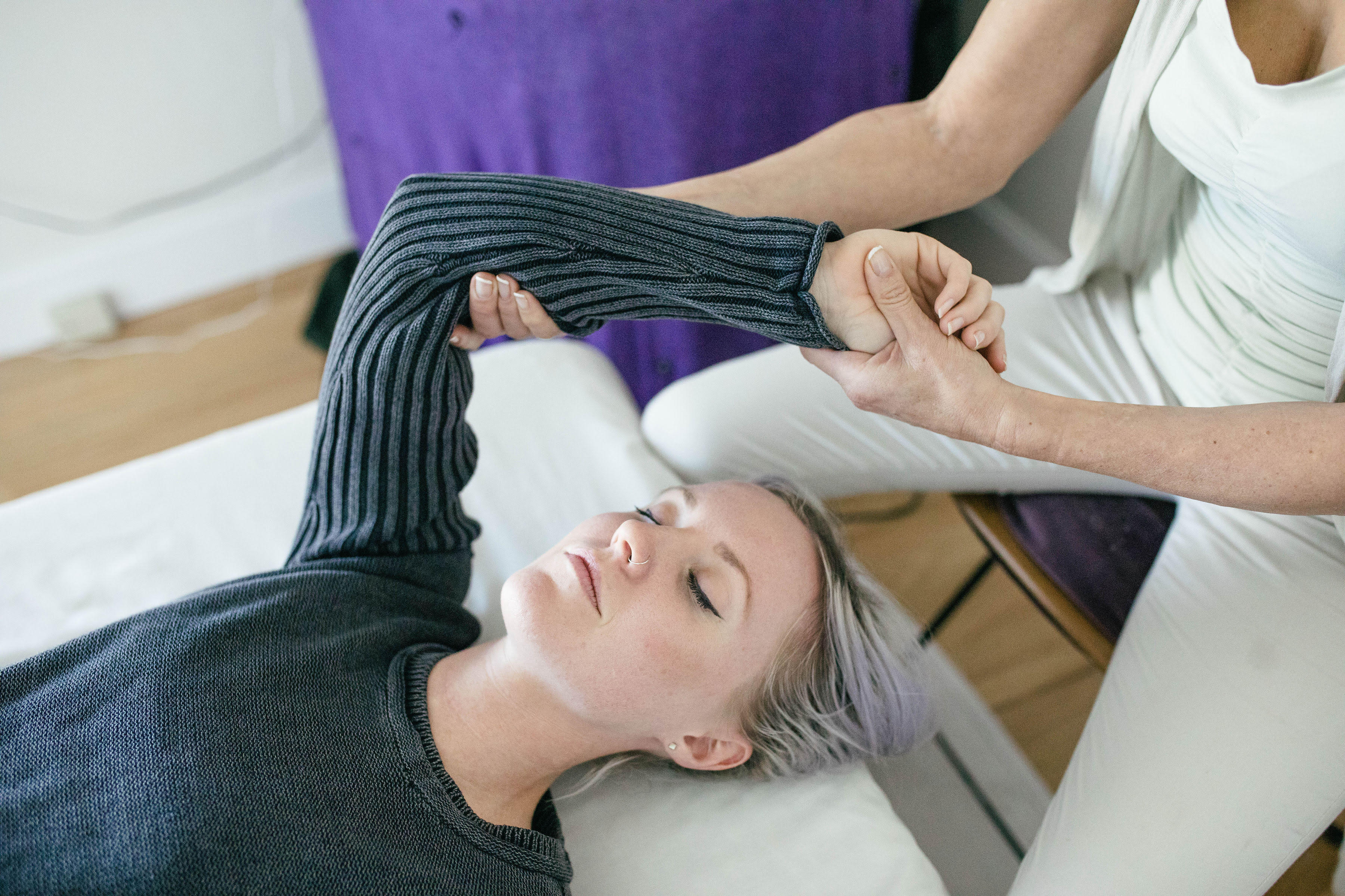 A practitioner gently supports a client’s arm during a hands-on movement session.